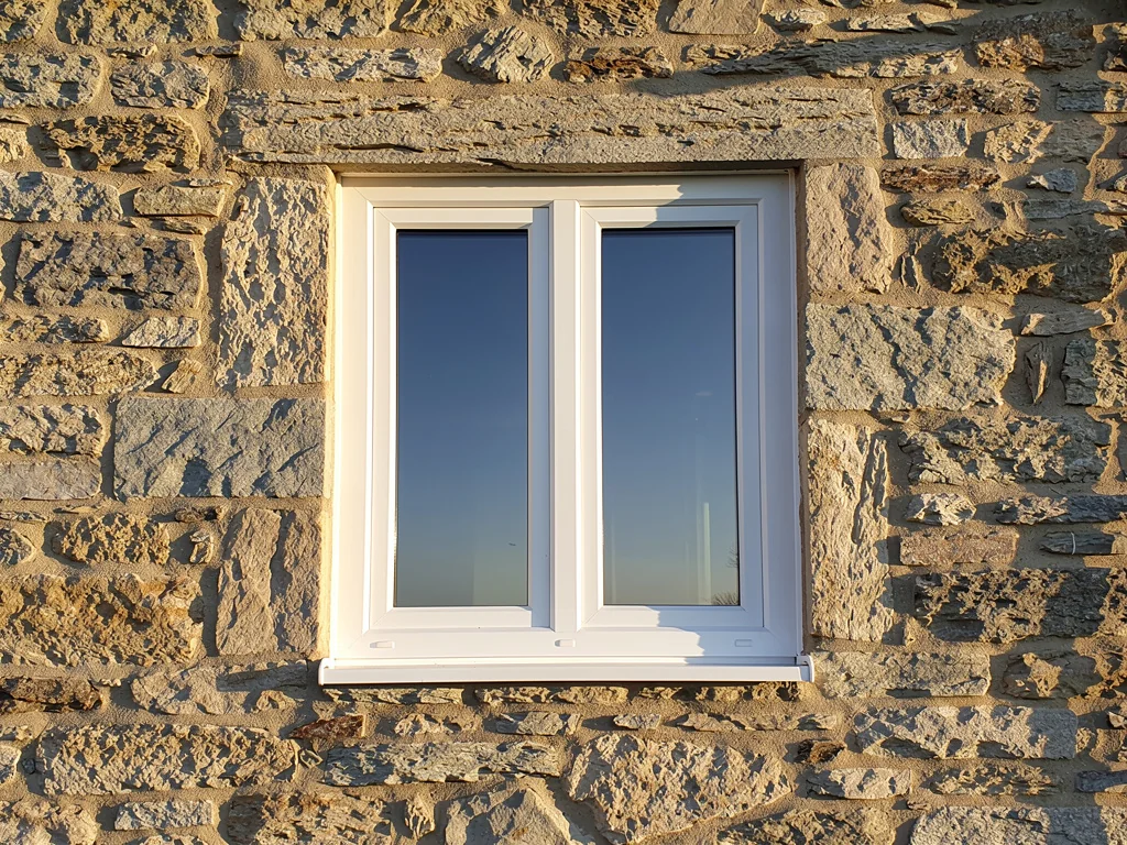 Fenêtre PVC double vitrage posée en rénovation sur une façade en pierre